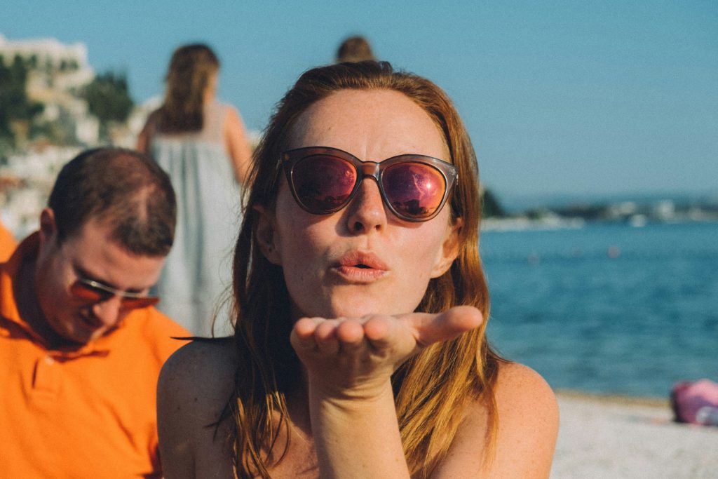 Girl with sunglasses on blowing kiss to the camera