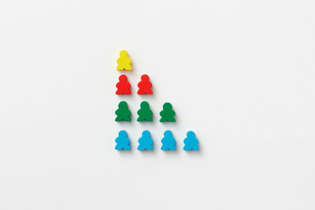 Small men shaped out of plastic, stacked on top of one another - one yellow, two red, three green and four blue.