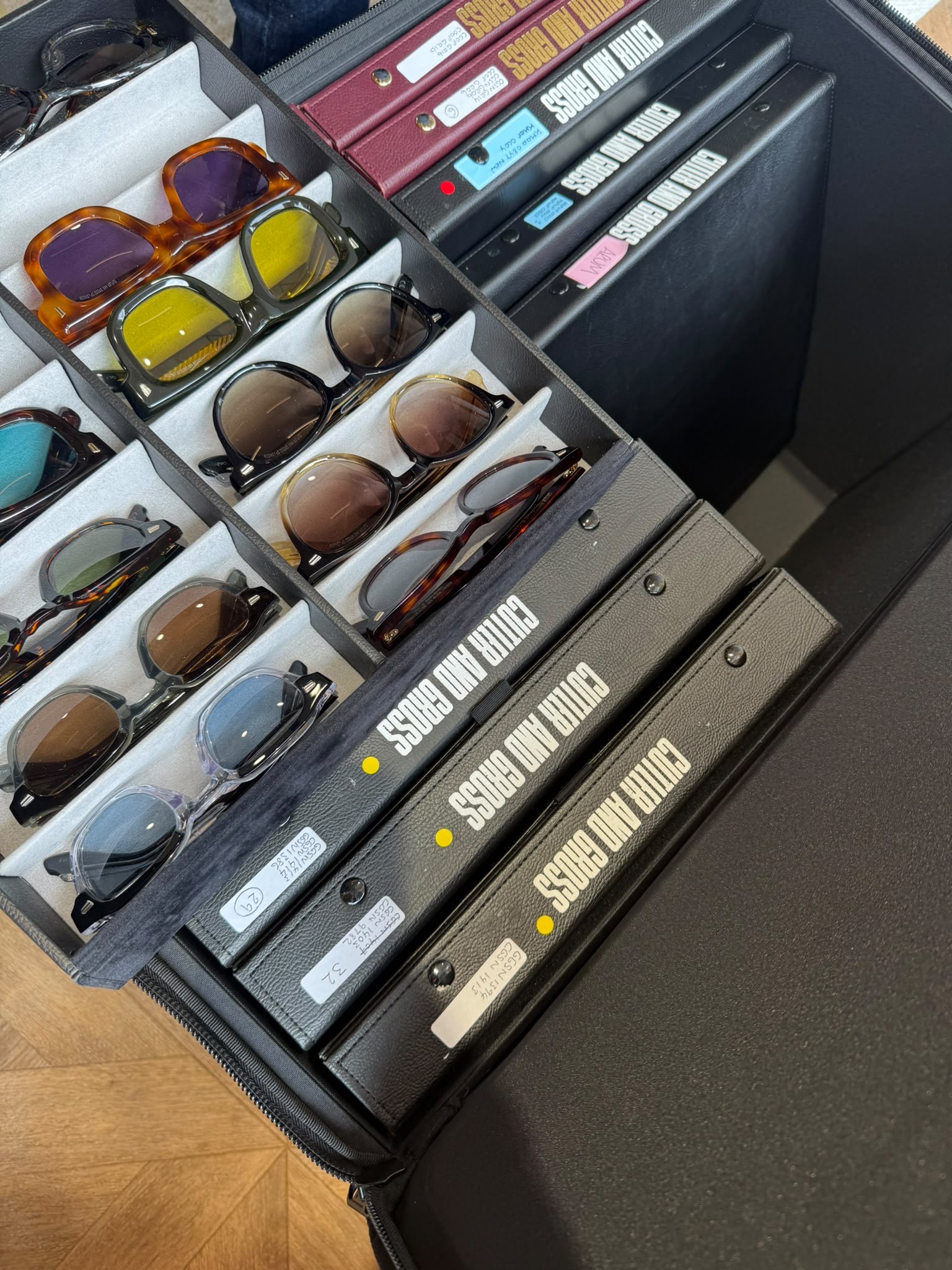 Selection of Cutler and Gross designer sunglasses displayed in organised travel cases, showcasing a variety of handcrafted acetate frames and tinted lenses for an exclusive eyewear styling consultation.